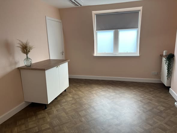 A light room with a window, white cabinet and parquet floor